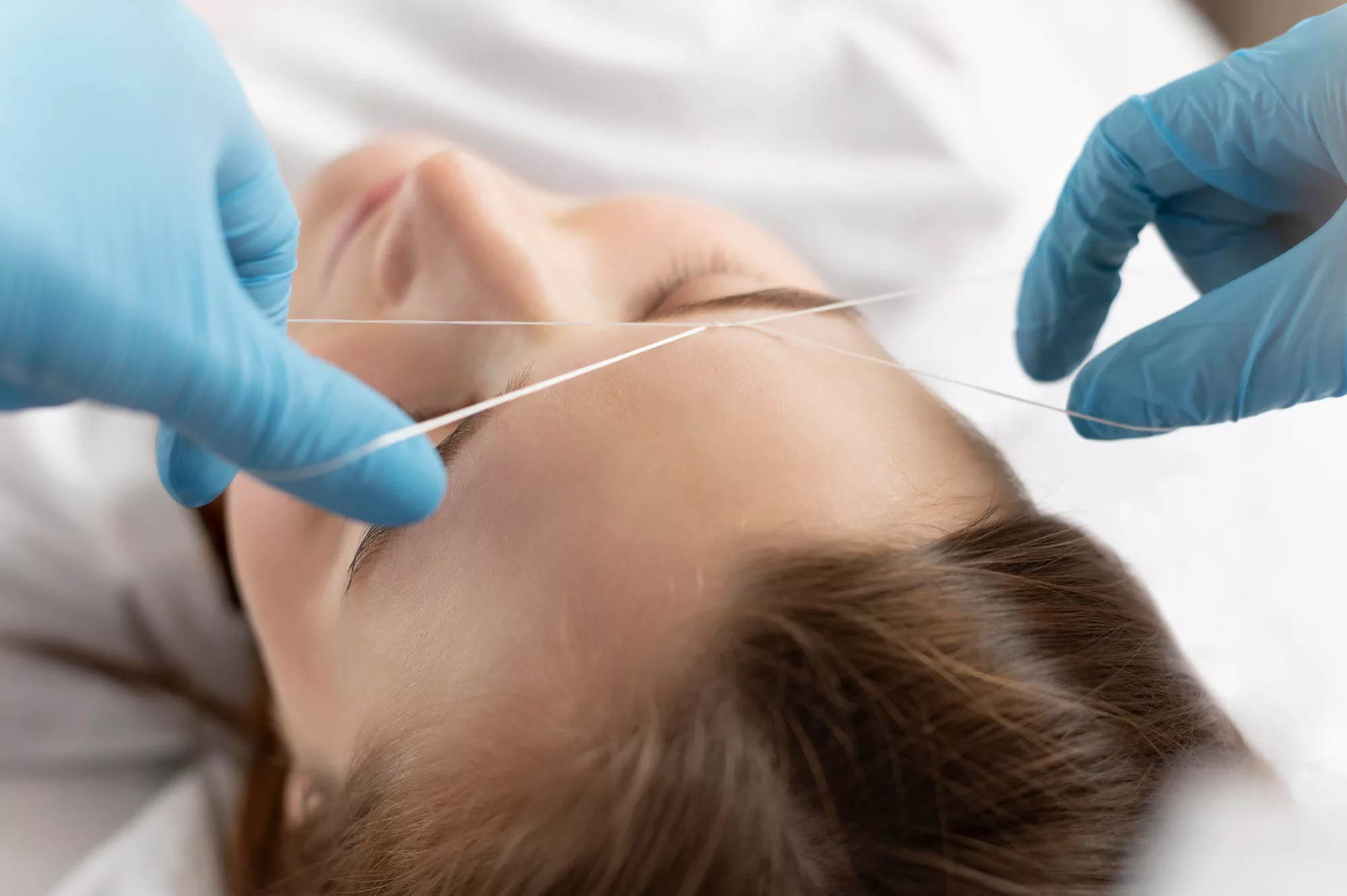 Depilación de cejas con hilo en un salón de belleza profesional