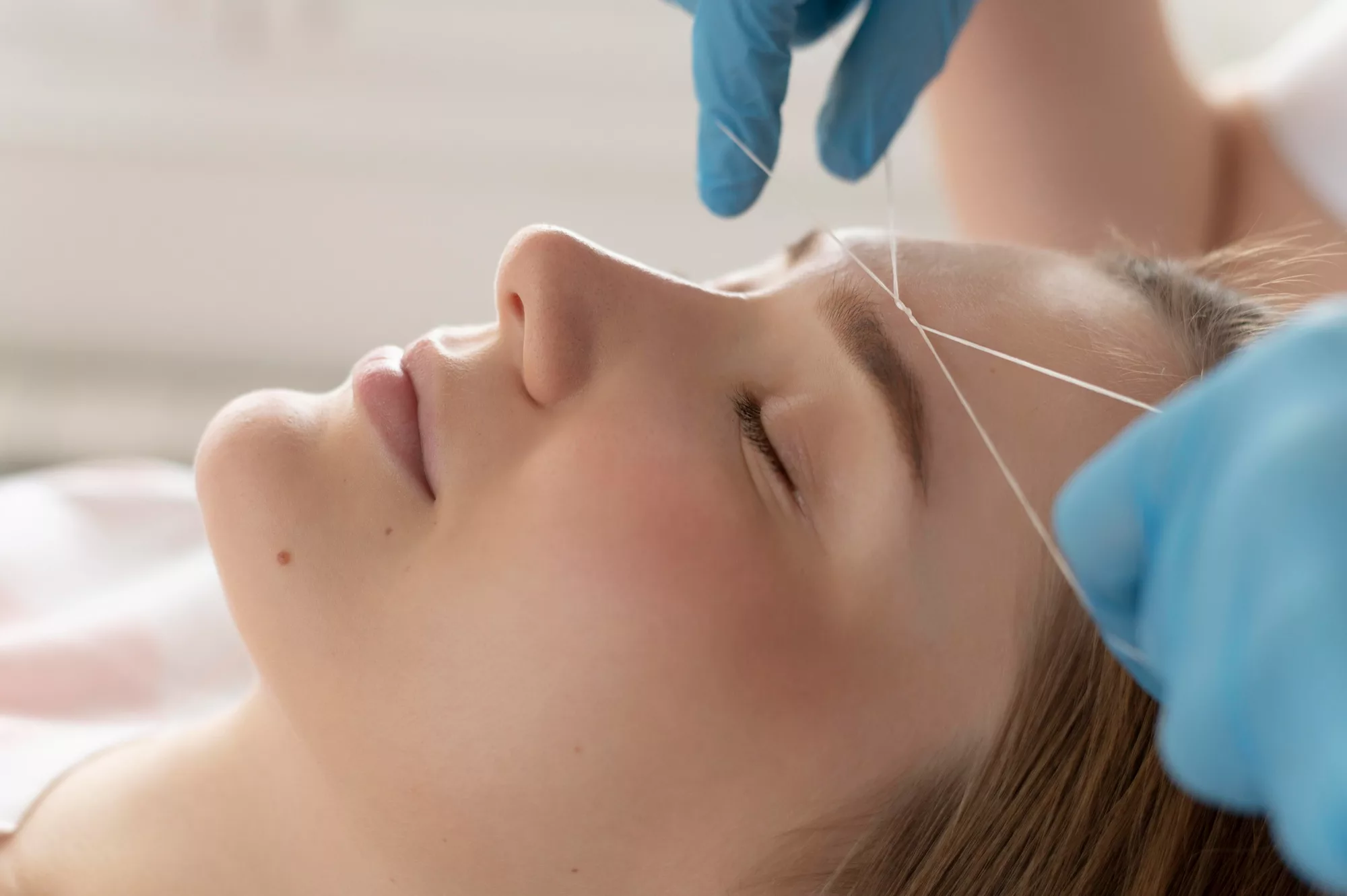 Depilación de cejas con hilo en salón de belleza profesional