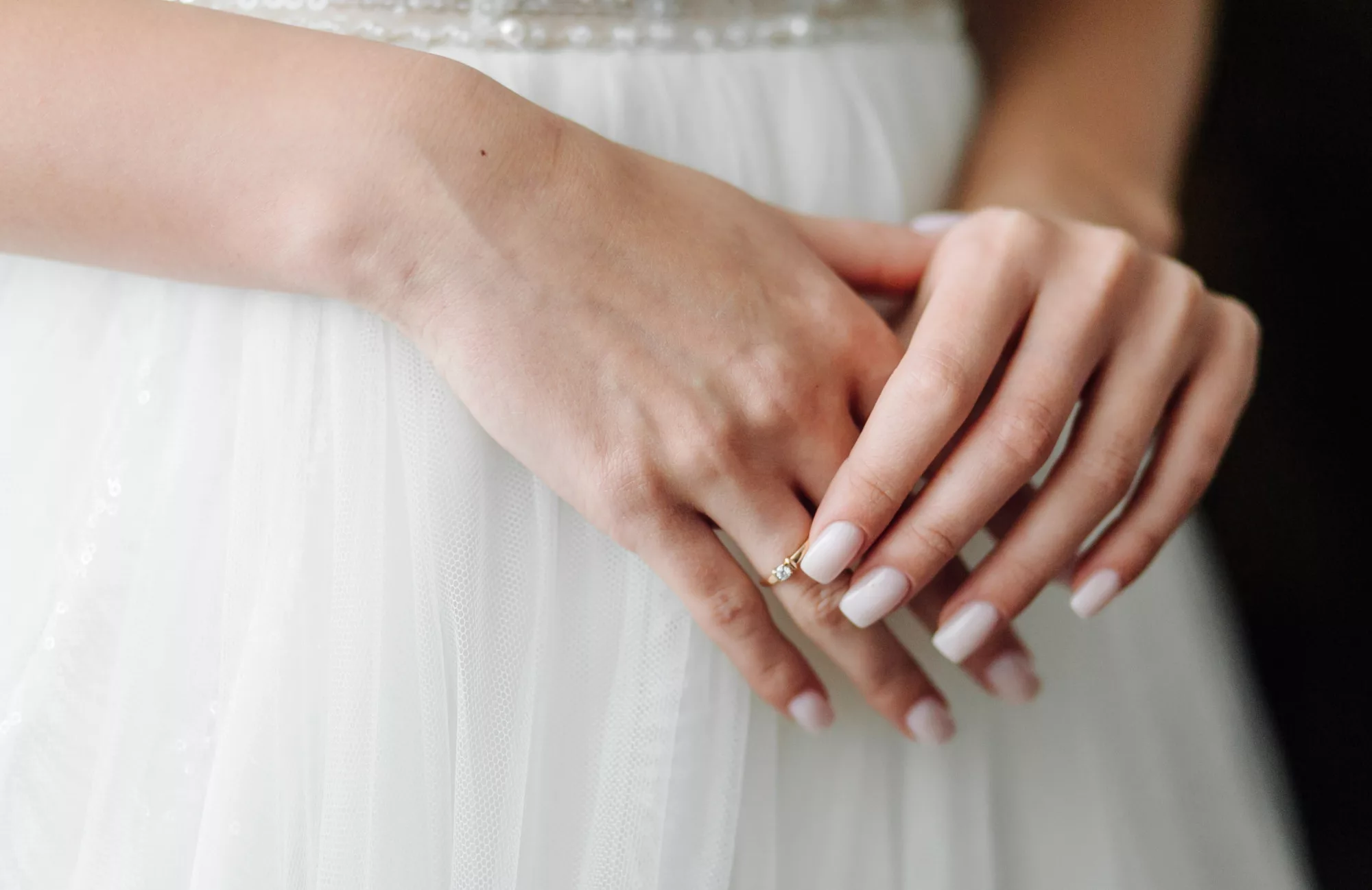 Manos de novia sosteniendo su vestido de boda blanco elegante